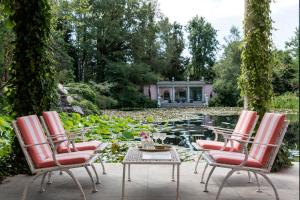 a patio with three chairs and a table in front of a pond at Relais La Foleia - Luxury Villa with private lake in Veruno