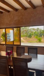Un comedor con una mesa y un gran ventanal. en Waridi Room at Lulu Sands, en Watamu