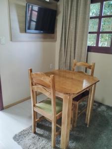 a wooden table with two chairs and a television at Pousada Deck 950 - Cambará do Sul in Cambará