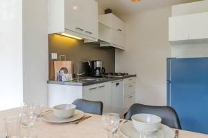 een keuken met een tafel met stoelen en een koelkast bij Hello Zeeland - Appartement Beatrixstraat 27 in Domburg