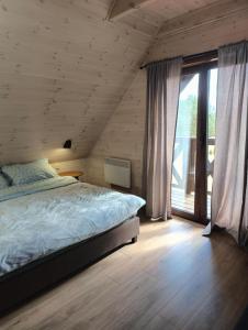 Un dormitorio con una cama y una ventana grande. en Wdzydzka Chatka, en Wdzydze Tucholskie