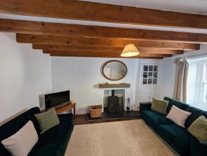 a living room with a green couch and a tv at Cosy Beach Cottage - Cawsand in Cawsand