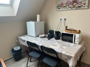 a table with a microwave and two chairs and a microwave at chambre Mont Fleuri in Halluin