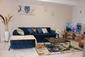 a living room with a blue couch and a table at Appartement BIKA à 5 mn de l'aéroport d'Ivato - navette privée gratuite in Talata-maty