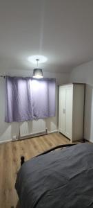 Habitación con cama y ventana con cortinas moradas. en Crystal Barking Service Accommodation, en Barking