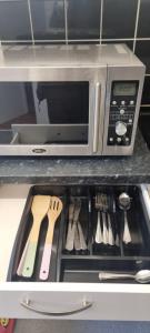 un cajón en una cocina con microondas y utensilios en Crystal Barking Service Accommodation, en Barking