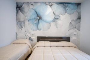 una camera con due letti con fiori blu sul muro di Blue Dream Suites a Salerno