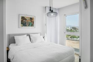 a white bedroom with a bed and a window at Rivi Luxury 42 Suites - By SEAELO EILAT in Eilat