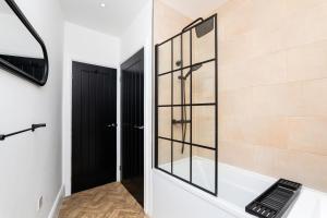 a glass shower in a bathroom with a black door at 2 Bedroom Apartment-Free Parking in Hawick