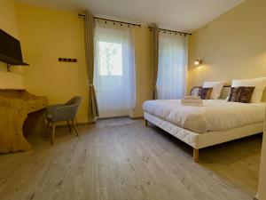 a bedroom with a bed and a desk and a chair at La chaumette in Pannessières