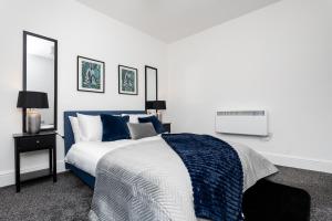 a bedroom with a blue and white bed and a mirror at 2 Bedroom Apartment-Free Parking in Hawick