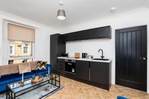 a kitchen with black cabinets and a blue couch in a room at 2 Bedroom Apartment-Free Parking in Hawick +16 photos