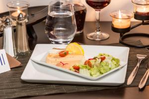 a plate with a piece of tofu and salad on a table at Hôtel Inn Design & Restaurant Sedan in Sedan
