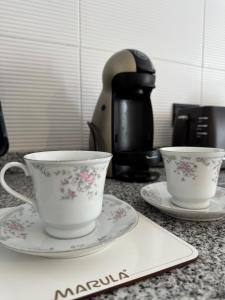 two cups and plates on a counter with a coffee maker at 3H MALARGUE Duplex calefacción por radiadores in Malargüe
