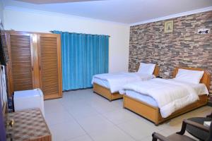 a bedroom with two beds and a brick wall at Hotel Taj Palace in Sialkot