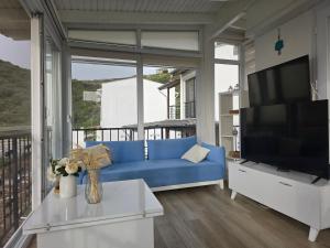 a living room with a blue couch and a large window at Sevinc Akasya House in Milas