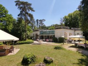 a large house with a yard with benches and umbrellas at Le Moulin d'Andé in Andé