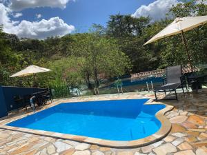 a swimming pool with an umbrella and a table and chairs at Estância dos Lagos in Cláudio