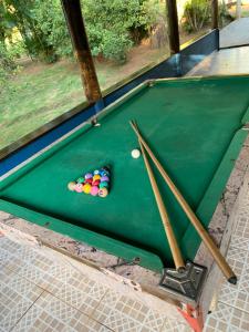 a pool table with pool balls and two cue sticks at Estância dos Lagos in Cláudio