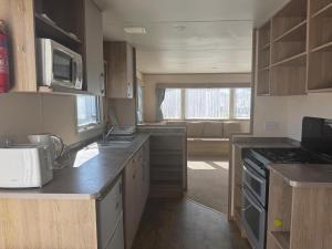 a kitchen with a sink and a stove top oven at Great Caravan At Dovercourt Holiday Park, Essex Ref 44206V in Great Oakley