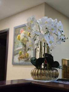 een vaas gevuld met witte bloemen op een tafel bij Hotel-Apartment NMP in Tbilisi City