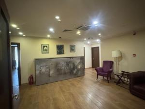 een woonkamer met een grote televisie en een paarse stoel bij Hotel-Apartment NMP in Tbilisi City