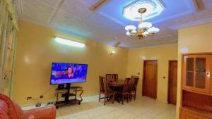 a living room with a television and a dining room table at AG appart'hôtel villas in Ouagadougou