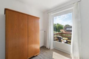 Habitación con armario de madera y ventana grande. en Wiebke, en Büsum