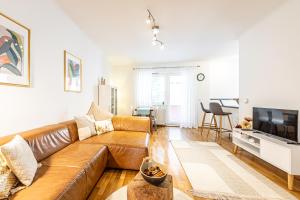 a living room with a brown leather couch and a television at Genuine Vienna Home by JR City Apartments in Vienna