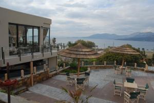 eine Terrasse mit Tischen, Stühlen und Sonnenschirmen in der Unterkunft Alykes in Marmarion
