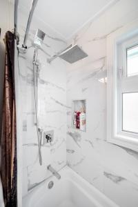 a white bathroom with a shower and a tub at Beautiful Home In A Prime Location in Winnipeg +29 photos