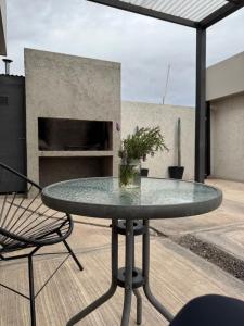 a glass table and chairs on a patio at 3H MALARGUE Duplex calefacción por radiadores in Malargüe