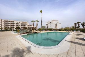 a swimming pool in a resort with palm trees and buildings at Sol do Atlântico in Portimão