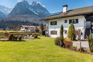 a house with a deer in a yard with mountains at Ferienhaus Frühholz - Fewo Alpspitz in Grainau