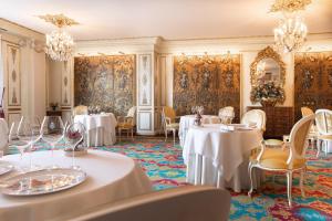 a dining room with white tables and chairs and chandeliers at Hotel Le Negresco in Nice