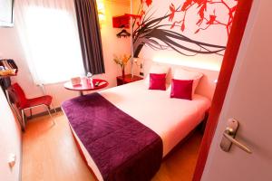Una habitación de hotel con una cama con almohadas rojas. en Hotel Inn Design Sedan, en Sedan
