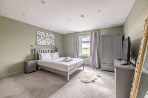 1 dormitorio con cama, TV y espejo en FAMILY FRIENDLY ESCAPE IN ETON, COUNTRYSIDE VIEWS with Hot Tub, en Eton