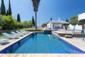 une piscine avec des chaises longues et une maison dans l'établissement True Local Village, à Loulé