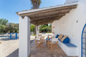 un patio avec une pergola en bois et une table et des chaises dans l'établissement True Local Village, à Loulé