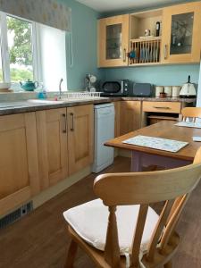 una cucina con mobili in legno, un tavolo e un lavandino di Samuel cottage a Caernarfon Altre 22 foto