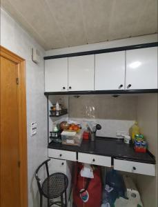 テラサにあるHabitación privada dobleのキッチン(白いキャビネット、黒いカウンタートップ付)