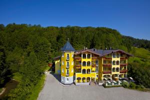 una vista aerea di un grande edificio giallo di Hotel Fischerwirt Natur WaldSPA a Faistenau