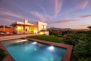 a villa with a swimming pool in front of a house at Noordhoek Sunset Villa in Flat Acres
