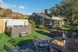 ペンリンダイドライスにあるRhiwgochのホットタブ、テーブル、椅子が備わる裏庭