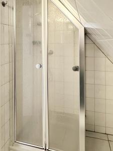 a shower with a glass door in a bathroom at Hüs Sanskiin Ferienwohnung *Eerdglüper* in Süddorf