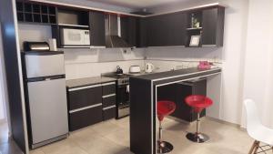 a kitchen with black and white appliances and red stools at Oikos VM in Villa María