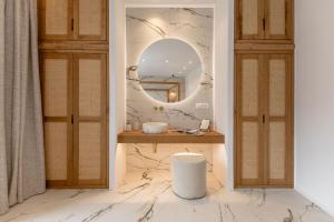 a bathroom with a vanity with a mirror and a stool at Elaia Home luxury village apartment for two Naxos in Galini +12 photos
