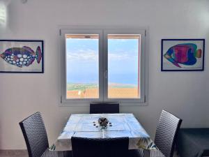 a dining room with a table and two windows at Appartamento con piscina e vista mozzafiato in Cascabraga +15 photos