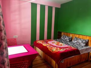 a bedroom with a bed with a red and green wall at Snow View Guest House in Kulu