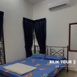 a bedroom with a bed with blue sheets and a window at Homestey de Usraty in Kampung Sungai Baharu